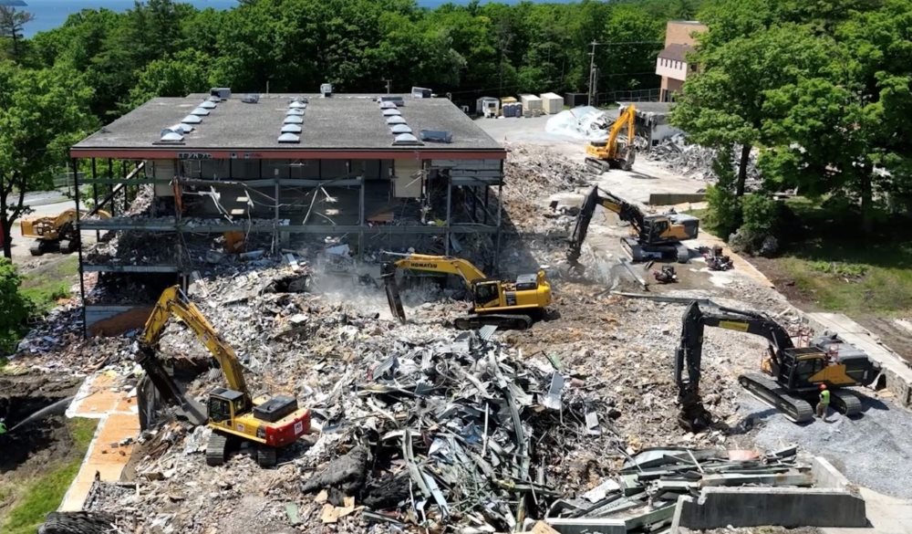 six excavators performing structural demolition on high school campus